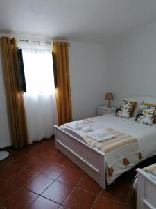 1 dormitorio con cama, ventana y suelo de baldosa en A Casa da Carolina, en Mértola