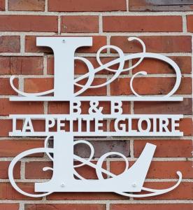 a white sign on a brick wall with the letter f and butterflyophone at La Petite Gloire in Pogum