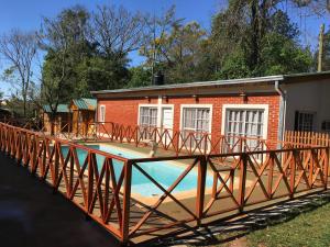 a pool with a wooden bridge in front of a house at Posada Enki in Puerto Iguazú