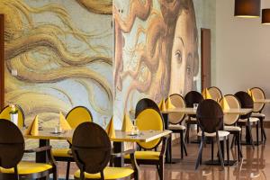 a dining room with tables and chairs and a large painting at Hotel Olympic in Ustroń