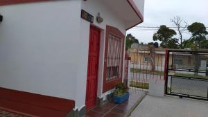 una puerta roja en el lateral de un edificio blanco en Complejo AleMar en San Clemente del Tuyú