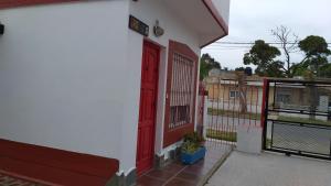 a red door on the side of a white building at Complejo AleMar in San Clemente del Tuyú