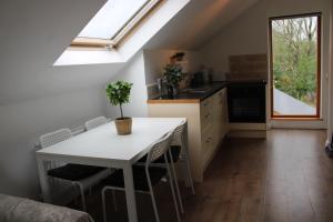 una cocina con una mesa y sillas blancas y una ventana en The Loft at Rock Cottage with hot tub, en Garvagh