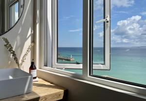 a bathroom with a window with a view of the ocean at Harbour View House in St Ives