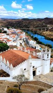 un gran edificio blanco con una ciudad junto a un río en A Casa da Carolina, en Mértola