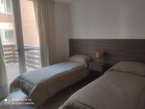 zwei Betten in einem Zimmer mit Fenster in der Unterkunft Libertador Norte Departamentos in Pinamar