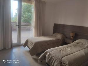 zwei Betten in einem Hotelzimmer mit Fenster in der Unterkunft Libertador Norte Departamentos in Pinamar