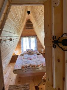 a bed in a wooden house with a window at Crângul Verde in Minciuneşti
