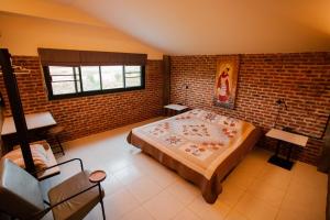 sypialnia z dużym łóżkiem i ceglaną ścianą w obiekcie SuanGlangNa w mieście Phrae