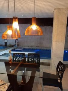 un tavolo in vetro con sedie e luci in una stanza di Lis zen suite 02 a Porto De Galinhas