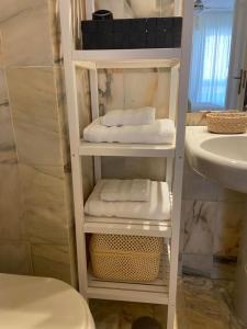 a bathroom with a white shelf with towels and a sink at Feria de Abril de Sevilla Apartamento a 30 metros de la portada Fantástico! No hay nada mejor! in Seville