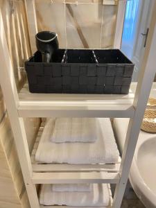 a bathroom shelf with a black basket on top of towels at Precioso apartamento Los Remedios Triana Plaza España y Centro Histórico in Seville +14 photos