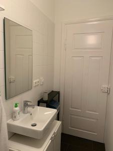 ein weißes Badezimmer mit einem Waschbecken und einem Spiegel in der Unterkunft Charmante Stadtwohnung im Textilviertel in Augsburg