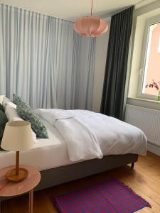 um quarto com uma cama com lençóis brancos e uma mesa em Charmante Stadtwohnung im Textilviertel em Augsburg