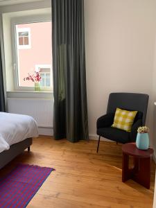 a bedroom with a bed and a chair and a window at Charmante Stadtwohnung im Textilviertel in Augsburg