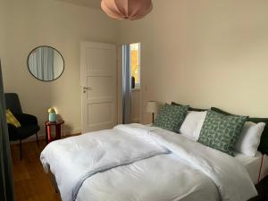 1 dormitorio con 1 cama blanca grande con almohadas verdes en Charmante Stadtwohnung im Textilviertel, en Augsburg