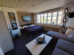 um quarto de hotel com uma cama e uma sala de estar em Toftegården Guesthouse - Rooms em Skagen