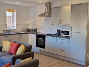 a kitchen with white cabinets and a blue couch at Pass the Keys 3 Devondale Bungalows Modern bungalow with parking near the beach in Dawlish