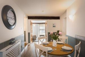 a dining room with a table and a clock on the wall at Blue Skies Apartment - Harbour Views in Torquay