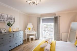 a bedroom with a bed and a dresser and a mirror at Blue Skies Apartment - Harbour Views in Torquay