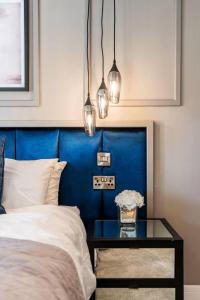 a bedroom with a blue headboard and a glass table at Clwyd Gate Manor Pool Sauna HotTub Cave Wales in Ruthin