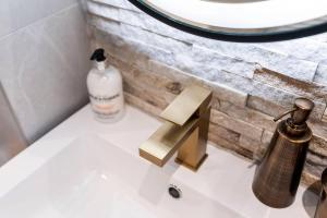 a bathroom sink with a soap dispenser on it at Clwyd Gate Manor Pool Sauna HotTub Cave Wales in Ruthin