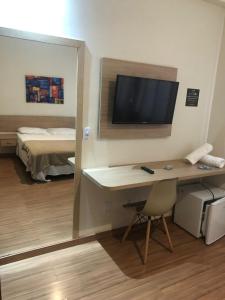 a room with a desk with a television and a bed at Pousada HD in Nova Friburgo