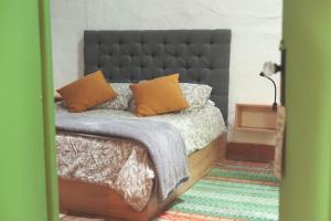 Schlafzimmer mit einem Bett mit schwarzem Kopfteil und orangefarbenen Kissen in der Unterkunft La Liebre bed and breakfast in El Retiro
