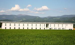 un edificio blanco con un campo de césped delante de él en Best sleep Hotel, en Spielberg