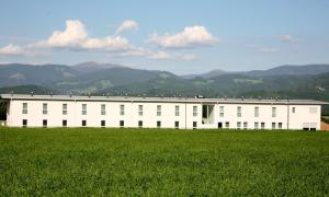 a white building with a grass field in front of it at Best sleep Hotel in Spielberg