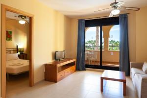 un soggiorno con divano, TV e finestra di Apartamentos Playamarina a Isla Canela
