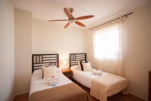 two beds in a room with a ceiling fan at Apartamentos Paraiso Playa in Vera