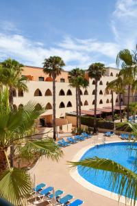 a resort with a pool and chairs and palm trees at Apartamentos Playamarina in Isla Canela