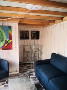 sala de estar con sofá azul y techo en Romantic Woodhouse casita camping, en Aguatona