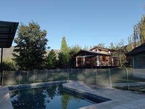 una piscina con valla y una casa en Casa La Encantada, en el pedemonte mendocino en Luján de Cuyo