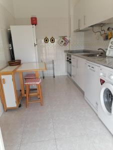 a kitchen with a table and a washing machine at Leonel Barcelos in Quarteira