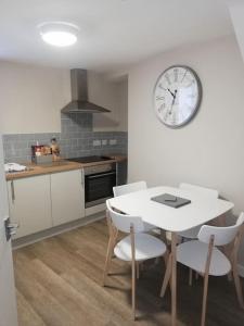 a kitchen with a table and a clock on the wall at Siop Iwan a Menna in Caernarfon