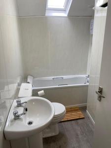 a bathroom with a sink and a toilet and a tub at Siop Iwan a Menna in Caernarfon
