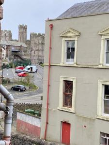 a white building with a red door and a castle at Siop Iwan a Menna in Caernarfon