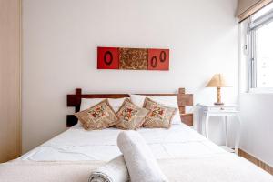 a bedroom with a white bed with pillows at Apê com janelão | 300 m da Av. Paulista in São Paulo