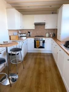 cocina con armarios blancos y suelo de madera en The Cottage, Hill Top Stables en Esh