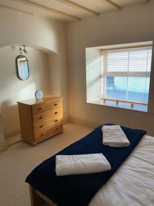 a bedroom with a bed and a dresser and a window at The Cottage, Hill Top Stables in Esh