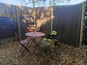 a table and four chairs in front of a fence at Roulotte Authentique 'Le Temps d une Pause" en face du Beaujolais - Climatisation et Borne recharge véhicule électrique in Montmerle Sur Saône