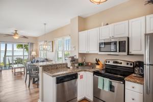 a kitchen with white cabinets and appliances and a dining room at Palm Breeze in Duck Key