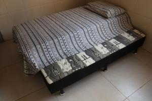 Una cama con un edredón blanco y negro. en Casa com 03 quartos tendo 02 com ar condicionado no asfalto a 1,5 km do centro, en Chapada dos Guimarães