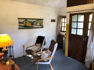 a living room with two chairs and a door at La Cabaña Celeste in Cuchilla Alta