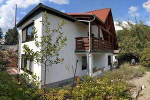 a white house with a balcony on top of it at Ferienwohnung in ruhiger Lage direkt am Wald in Heidenheim an der Brenz