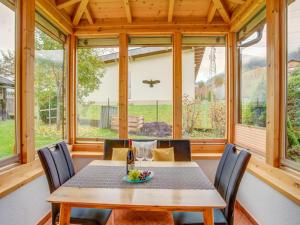 uma sala de jantar com mesa, cadeiras e janelas em Lovely Apartment in Picturesque Niedernsill with Garden em Niedernsill