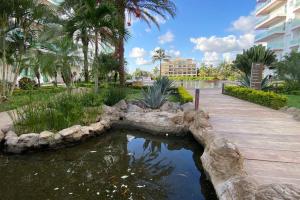 einen Teich in einem Park mit Palmen und einem Gebäude in der Unterkunft Habitación hotelera 5min de la playa by G P S rentas in Mazatlán