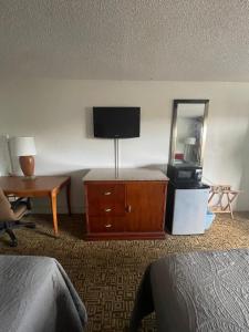 um quarto de hotel com uma televisão e uma cómoda com um espelho em Ambassador Inn em Kissimmee